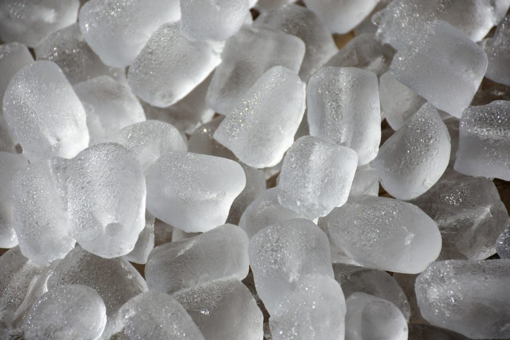 A close heap of cylindrical ice cubes, frosted and beaded with meltwater