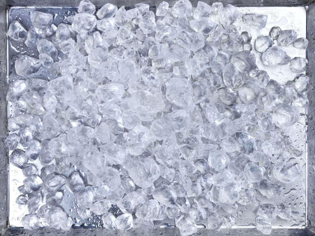 An ice bin filled to the top with clear cubes, seen straight down